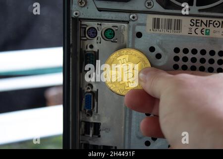 The back side of a computer with sockets, cables, and a bitcoin holding hand. Showing the importance of computer for mining. Stock Photo