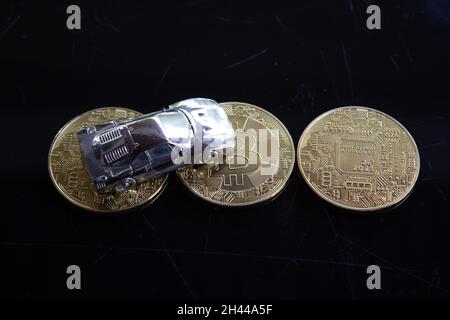 A shiny silver car with some bitcoin and a silver pen on a shiny black surface. Stock Photo