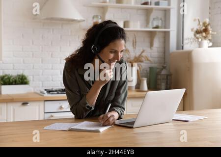 Woman elearning at home listen audio writes notes in copybook Stock Photo