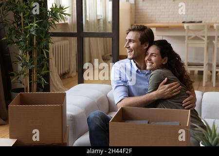 Happy married couple resting on sofa on moving day Stock Photo