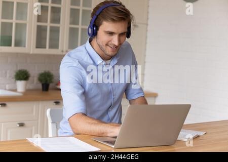 Handsome man wear headset looks at laptop listens audio course Stock Photo
