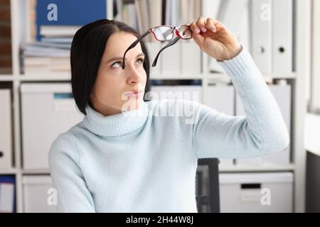 Tired young woman at workplace took off glasses closeup Stock Photo