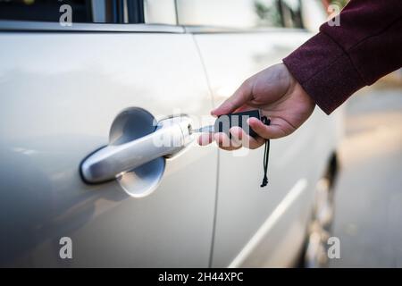 Close up on hand of unknown caucasian man holding car keys locking or unlocking the vehicle door Stock Photo