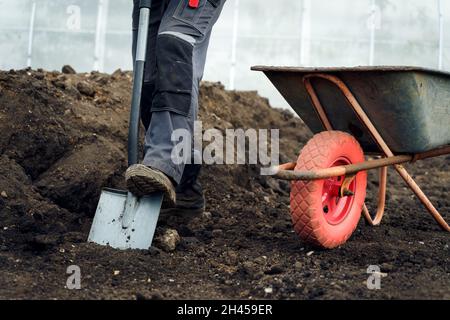 Working with garden tools, shovel and wheelbarrow on the site of a country house. Preparation for construction work Stock Photo