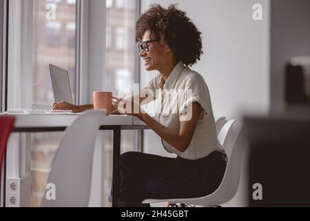 Pretty young lady enjoying her job in modern coworking Stock Photo