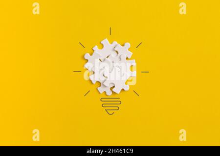 Light bulb from puzzles on yellow background. Inspiration and creative idea concept. Top view with copy space. Flat lay composition. Stock Photo