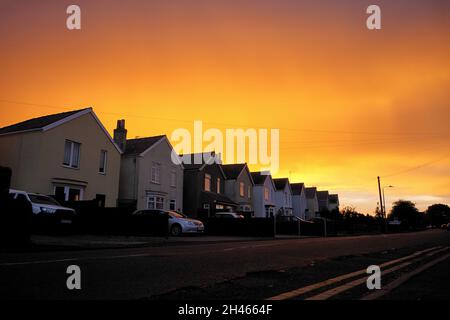low angle view of a row of houses against a stunning orange sunset sky Stock Photo