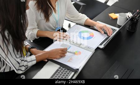Cropped image of two successful and smart businesswomen in a financial team working and analysing on business data together. Stock Photo