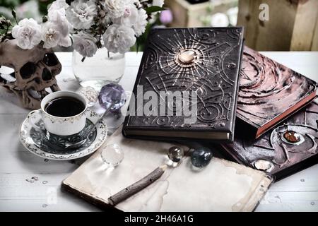 Vintage grunge still life with old witch book, diary, cup and skull on empty table.  Esoteric, occult and mystic concept for witchcraft Stock Photo