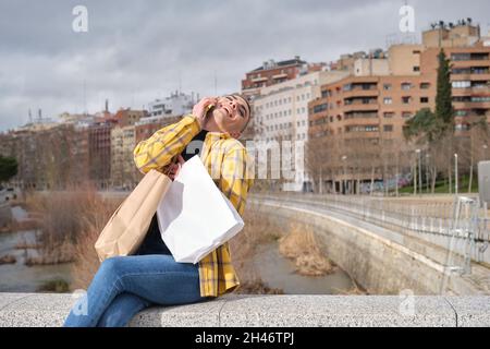 Young man with makeup on speaking and laughing on the smartphone. Stock Photo