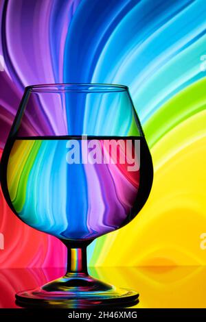 Abstract image of a cognac glass on a colored background with curves and a mirror surface Stock Photo