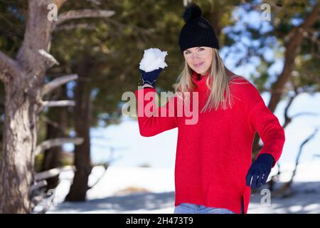 Young woman throwing snowballs forward in a snow-covered forest in the mountains Stock Photo