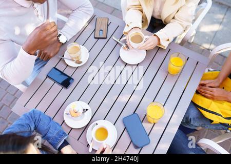 Top view of people drinking coffee, juice and tea sitting at the table on the terrace of a bar. Stock Photo
