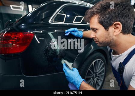 Car mechanic covering car back with degreaser fluid Stock Photo