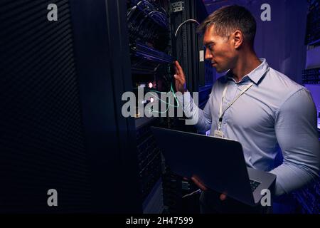 Experienced data center system administrator running equipment diagnostics Stock Photo