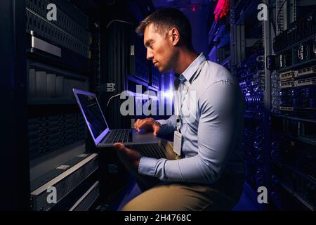 Serious focused system administrator checking data center equipment Stock Photo