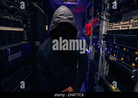 Male hacker standing in dark server room Stock Photo