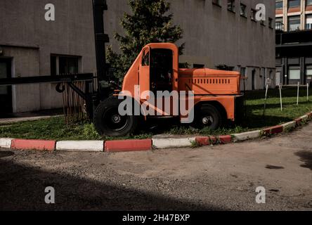 Concept of warehouse. the forklift on the street near wall. retro loader near the warehouse. old loader Stock Photo