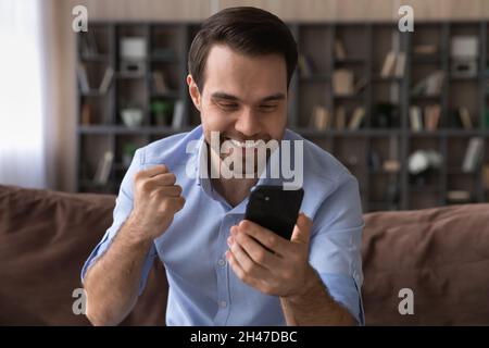 Emotional happy young man celebrating online success. Stock Photo