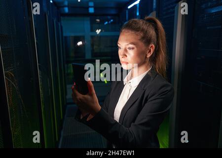 Female technician works on cellphone in data center Stock Photo