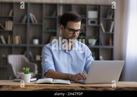 Happy young businessman in eyeglasses working on computer. Stock Photo