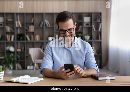 Smiling handsome young man using cellphone applications. Stock Photo