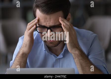 Frustrated young businessman suffering from headache. Stock Photo
