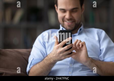 Joyful young man using cellphone applications at home. Stock Photo