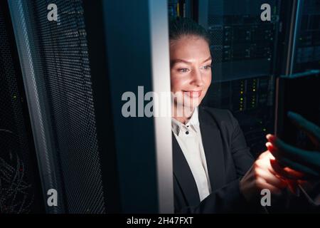 Cheerful woman network engineer working in server room Stock Photo