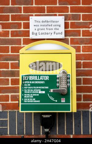 Defibrillator, emergency medical equipment at a village hall with a plaque stating it was funded by the Big Lottery Fund, Hampshire, England, UK Stock Photo