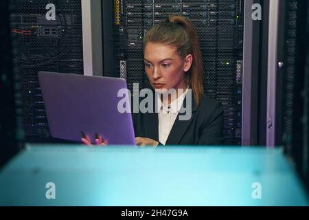 Technician performing maintenance on servers with laptop in data center Stock Photo