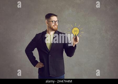 Man holds a painted yellow light bulb in his hand, which symbolizes a wonderful idea. Stock Photo