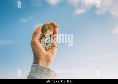 Vintage compass in male hands against the blue sky. Stock Photo