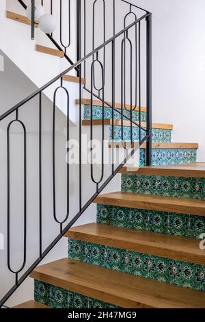 A close-up of a staircase made of wood and Armenian green ceramic tiles, and a metal railing designed this way Stock Photo