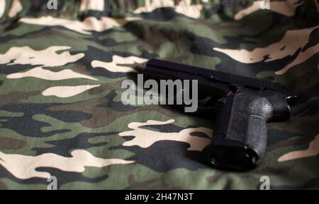 Black handgun, firearm on camouflage army green fabric Stock Photo