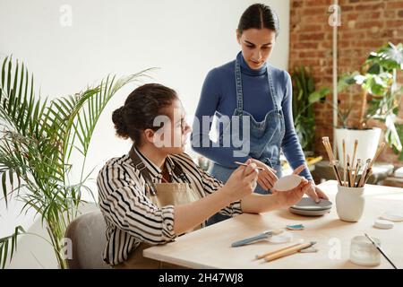 Warm toned portrait of young man and woman working in pottery studio, copy space Stock Photo