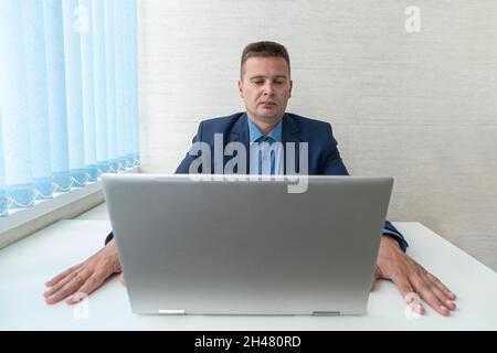businessman concentrating on computer work, looking at laptop screen, thinking. focused reading of information on a laptop in the office. The manager Stock Photo
