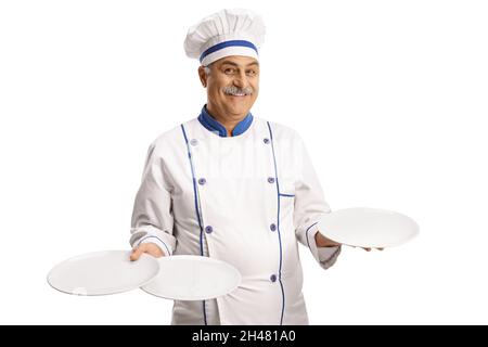 Cheerful mature chef smiling and holding three empty plates isolated on white background Stock Photo