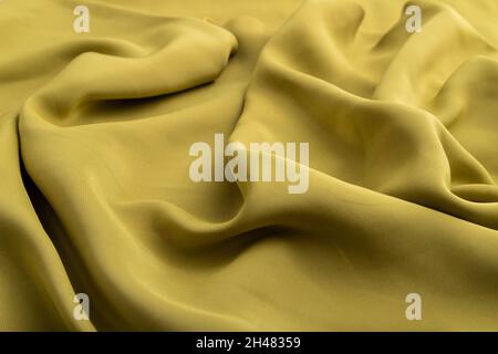 Fragment of green olive silk tissue. Side view, natural textile background and texture. wave concept, abstract. Stock Photo