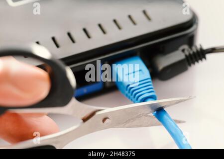 Scissors cutting LAN cable - no more internet. Stock Photo