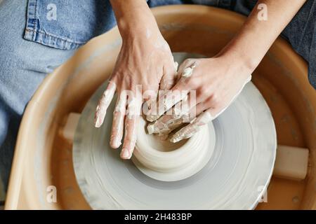 Top view close up of unrecognizable artist shaping clay on pottery wheel, copy space Stock Photo