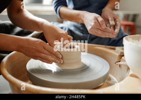 Close up young people working on pottery wheel together in handmade ceramics workshop, copy space Stock Photo