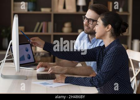 Happy young Indian employee working on online project with colleague. Stock Photo