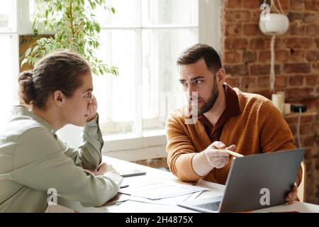 Portrait of two creative people using laptop while discussing design project in studio, copy space Stock Photo