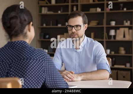 Concentrated young male applicant holding job interview with hr manager. Stock Photo