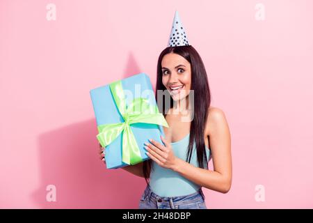 Portrait of attractive amazed cheerful girl holding in hands gift having fun isolated over pink pastel color background Stock Photo