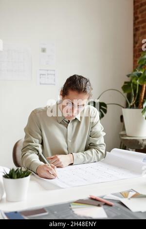 Minimal vertical portrait of creative young man working at table in studio Stock Photo