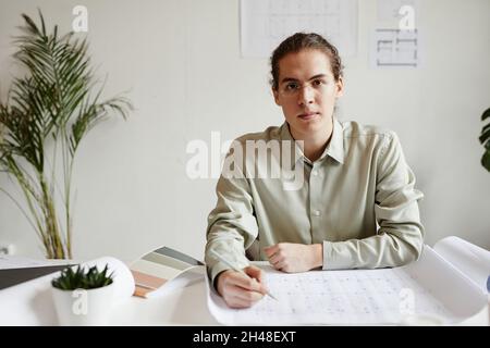 Minimal portrait of creative young man working at table in studio and looking at camera, copy space Stock Photo