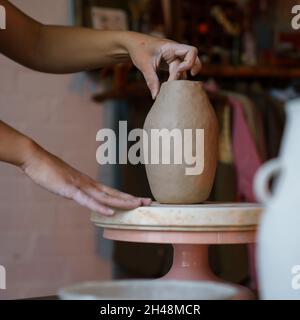 Pottery creation: female artist shaping sculpturing potter vase of raw clay. Girl artisan at work Stock Photo