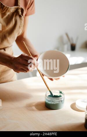 Minimal close up of unrecognizable female artist decorating ceramics in pottery workshop, copy space Stock Photo
